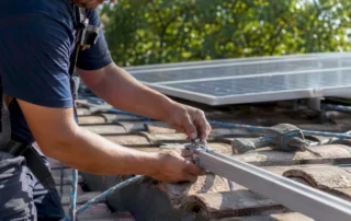 Mani al lavoro per sistemare il supporto di un pannello solare sul tetto di casa.