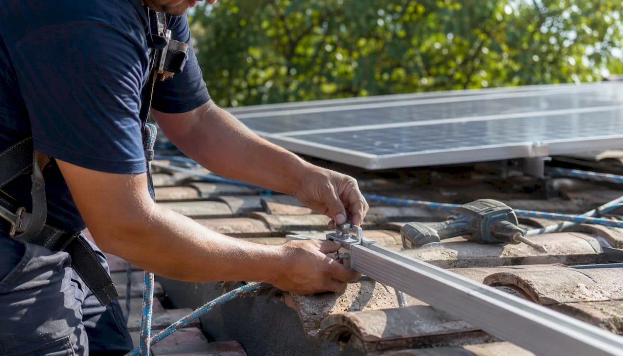 Mani al lavoro per sistemare il supporto di un pannello solare sul tetto di casa.