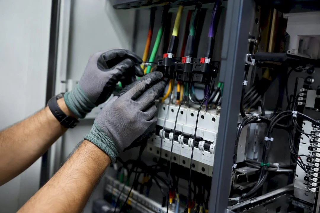 Mani che installano trasformatori di corrente su un quadro elettrico